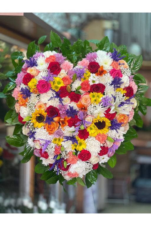 Multicolored full heart funeral arrangement by a Brooklyn florist, crafted with fresh blooms for a loving tribute.